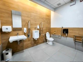 Barrier-free washroom with a wall-hung toilet flanked by fold-down grab bars and a wall-mounted sink