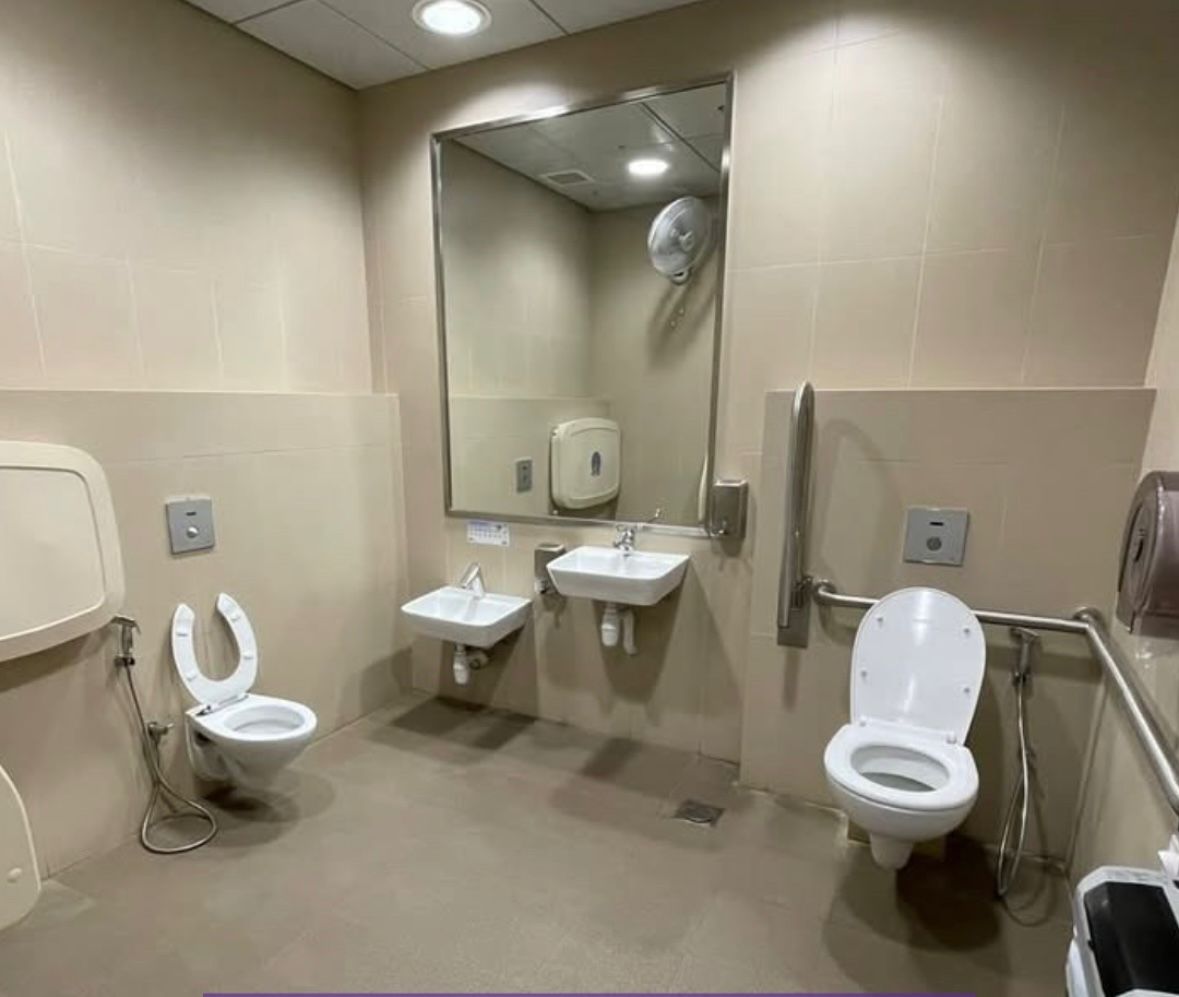 Accessible washroom with wall-hung toilets, support rails and wall-mounted basins