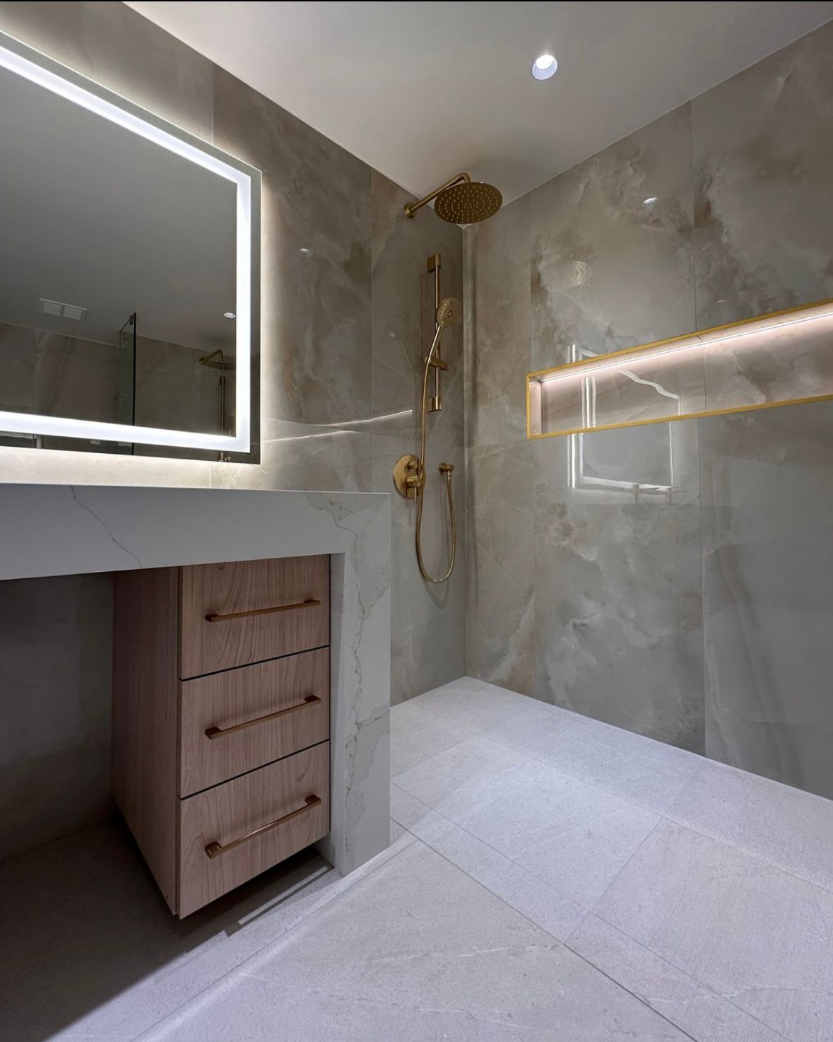 Luxury curbless walk-in shower with onyx-look marble walls, gold rainfall fixtures and a backlit niche